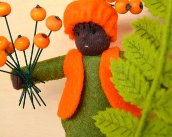 May include: A felt doll wearing a green outfit with an orange vest and a bright orange hat. The doll is holding a bouquet of orange felt berries with green stems.