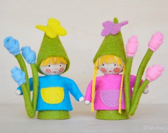 Two little gnomes holding a flower handmade out of wool felt and wool. Waldorf inspired for on the nature table.