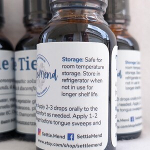 May include: Several small, brown glass bottles with black caps are arranged in a close-up shot. Each bottle has a white label with blue text, including instructions and the brand name "Settle.Mend". The bottles contain a liquid.
