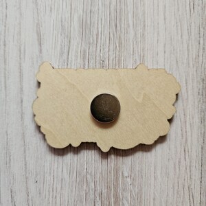 May include: A wooden cutout of a flower with a magnetic backing. The cutout is light brown and has a detailed design.