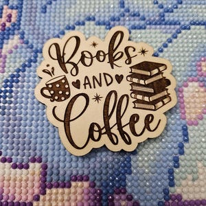 May include: A wooden sign with the text "Books and Coffee" in a decorative font. The sign features a stylised image of a coffee cup with polka dots and a stack of books.