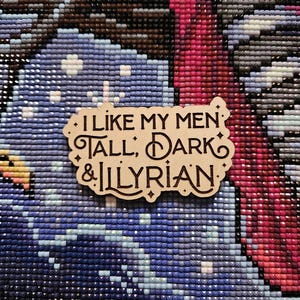 May include: A wooden sign with the text "I like my men tall, dark & Illyrian." The sign has a brown background and white lettering.