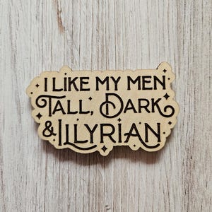 May include: A wooden sign with the text "I like my men tall, dark & Illyrian" in a decorative font.