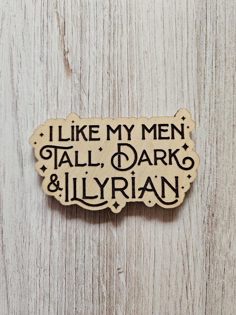 May include: A wooden sign with the text "I like my men tall, dark & Illyrian" in a decorative font.