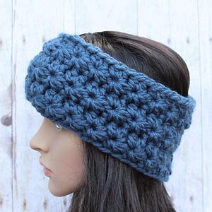 May include: A blue crocheted headband with a textured stitch pattern. The headband is wide and covers the ears.