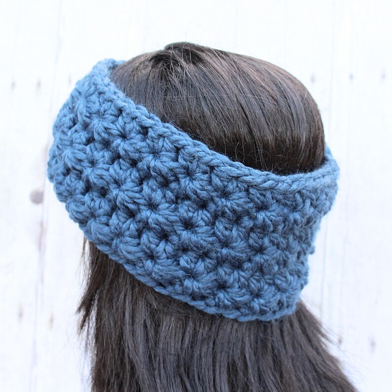 May include: A blue crocheted headband worn on a person's head. The headband is made with a simple stitch pattern.