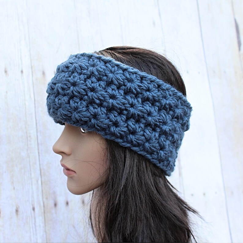 May include: A blue crocheted headband with a textured stitch pattern. The headband is worn on a person with long dark hair.