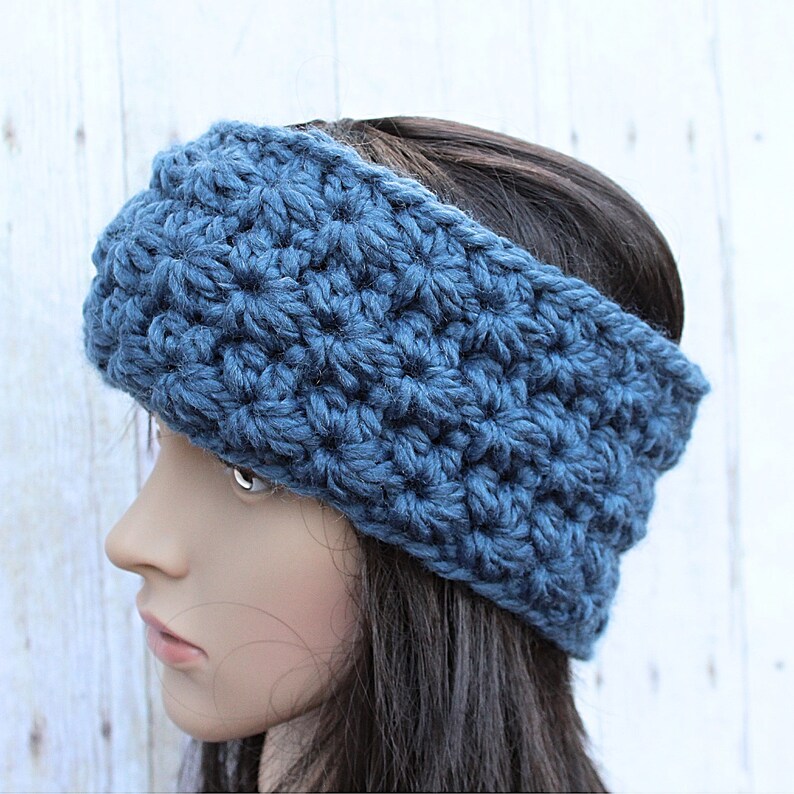 May include: A blue crocheted headband with a textured pattern. The headband is wide and covers the ears.