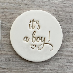 Può includere: Tagliapasta in plastica bianca con il testo "it's a boy!" e due piccoli cuori.