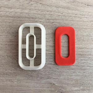 Puede incluir: Un cortador de galletas de plástico blanco con forma de número 0, junto a un cortador de galletas de silicona rojo con forma de número 0.