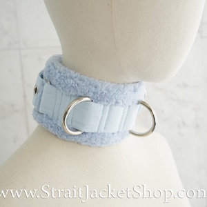 May include: A light blue faux fur choker with two silver metal rings. The choker is padded and has a stitched design. www.StraitJacketShop.com