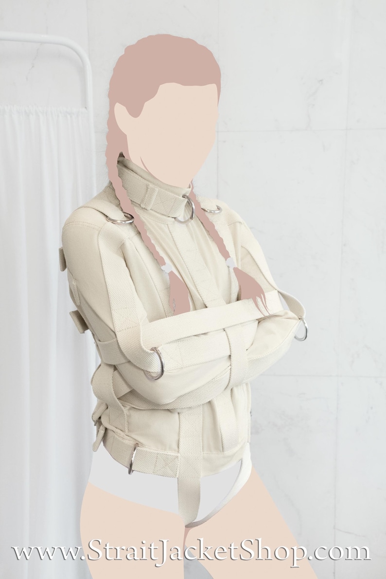 May include: A white canvas straitjacket with adjustable straps and buckles. The jacket is designed to restrain the arms and torso. The model is wearing the straitjacket with their arms crossed in front of them.