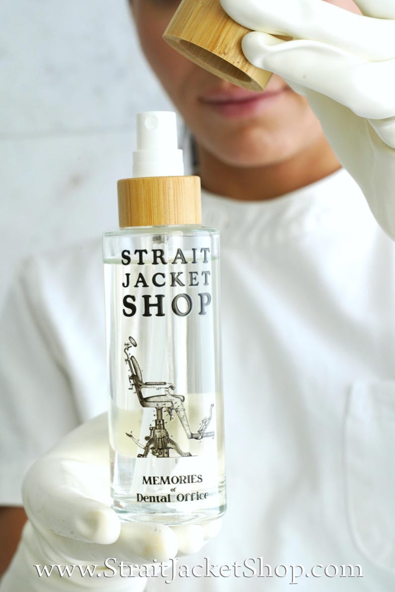 May include: A clear glass spray bottle with a bamboo cap and a white pump nozzle. The label features the black text "STRAIT JACKET SHOP" above a vintage illustration of a dental chair, with the words "MEMORIES of Dental Office" below.