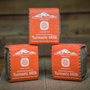 May include: Three bars of orange and brown soap with the text "Bounty Himalaya HANDCRAFTED Original & Pure" and "SOOTHING & CARING Turmeric Milk Himalayan Natural Body & Face Soap" printed on the labels.