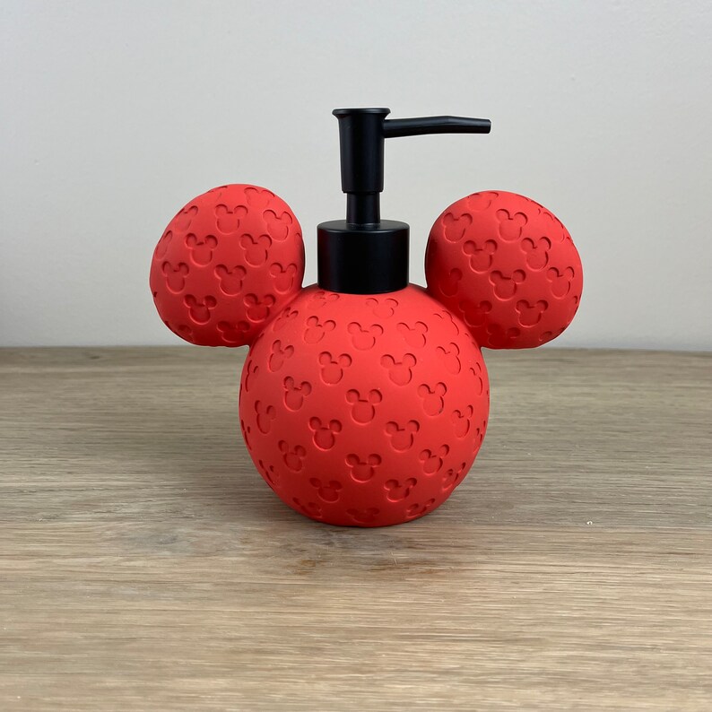 May include: Red soap dispenser shaped like Mickey Mouse's head with black pump and ears.