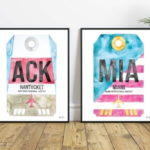 May include: Two watercolor prints of luggage tags with airport codes. The left print features a blue, red, and brown luggage tag with the code "ACK" and the text "NANTUCKET, NANTUCKET MEMORIAL AIRPORT". The right print features a blue, pink, and yellow luggage tag with the code "MIA" and the text "MIAMI, MIAMI INTERNATIONAL AIRPORT".