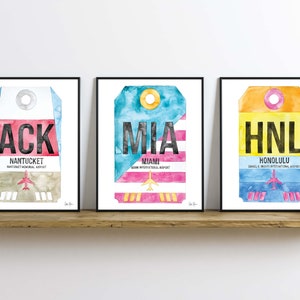 May include: Three framed watercolor prints of airport luggage tags. The tags are for Nantucket Memorial Airport (ACK), Miami International Airport (MIA), and Daniel K. Inouye International Airport (HNL).