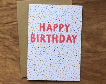 May include: A white card with a colorful confetti pattern and the text "Happy Birthday" in red.