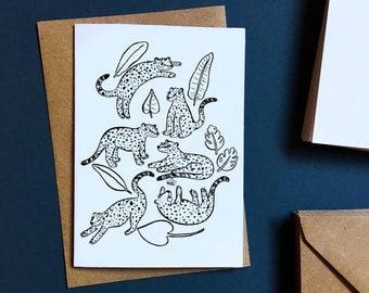 May include: A white card with black line drawings of leopards and leaves. The leopards are in various poses, some are walking, some are lying down, and some are standing. The leaves are simple and stylized.