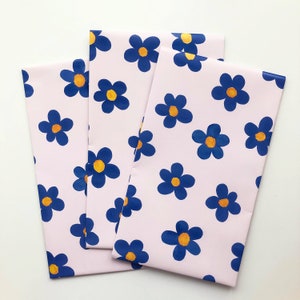May include: Three pink sheets of wrapping paper with a blue and yellow floral pattern. The flowers are stylized and have a retro look.