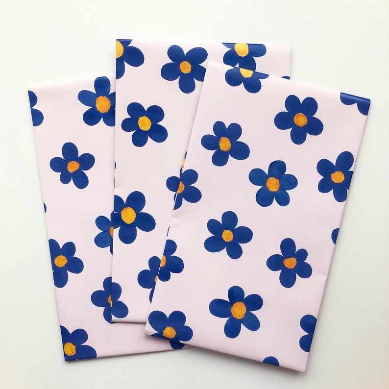 May include: Three pink sheets of wrapping paper with a blue and yellow floral pattern. The flowers are stylized and have a retro look.