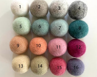 May include: A set of 16 wool balls in various colors, including white, gray, green, pink, peach, and red. The balls are numbered 1 through 16.