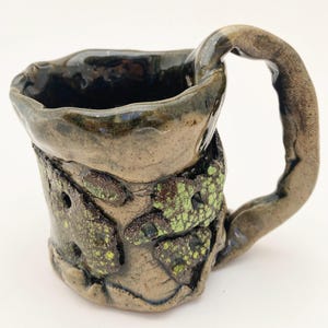 May include: A set of three ceramic mugs with a speckled, matte finish. The mugs are in shades of cream, light gray, and dark gray. Each mug has a simple, minimalist design, perfect for coffee or tea.