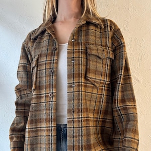 May include: A brown and black plaid flannel shirt with a collared neckline and long sleeves. The shirt has a button-up front closure and two flap pockets on the chest.