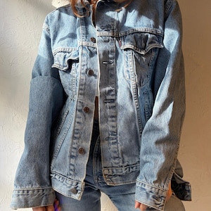 Puede incluir: Chaqueta vaquera azul claro con dos bolsillos en el pecho y cierre de botones. La chaqueta tiene un diseño clásico con cuello y mangas largas. La chaqueta vaquera se combina con unos vaqueros azules a juego.