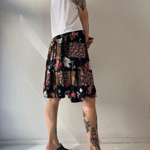 May include: A black and white patterned skirt with pink and gold accents. The skirt is knee-length and has a flowing silhouette.