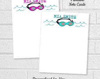 May include: Two white note cards featuring the text MIA SMITH in pink or teal, accompanied by a graphic of swimming goggles and blue hand-drawn waves. The cards include the text Printable Note Cards and Personalized for You.
