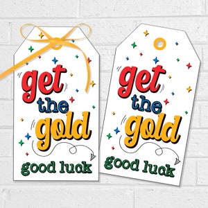 May include: Two white gift tags with a gold ribbon. The tags have a colorful confetti design and the text "get the gold good luck".