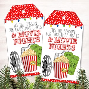 Könnte beinhalten: Zwei Geschenkanhänger mit einem rot-weiß gepunkteten Oberteil und dem Text "'Tis the season for Christmas lights & Movie Nights". Jeder Anhänger zeigt einen Popcorn-Eimer, eine Filmrolle und Kinokarten.