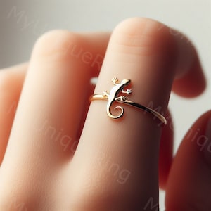 May include: A gold-toned ring with a lizard design. The ring is thin and delicate, and the lizard is detailed and realistic.