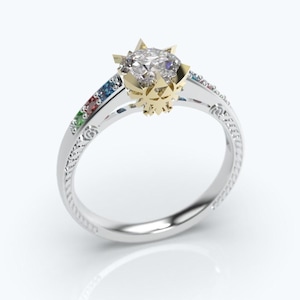 May include: A silver ring with a large, clear gemstone set in a gold and silver floral design. The ring features small, colorful gemstones along the band, adding a touch of color and sparkle. The band has an intricate, engraved pattern.