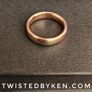 May include: A simple, polished, rose gold wedding band.