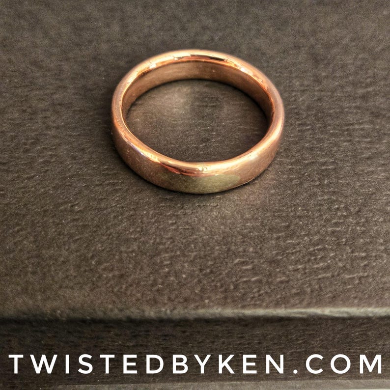 May include: A simple, polished, rose gold wedding band.