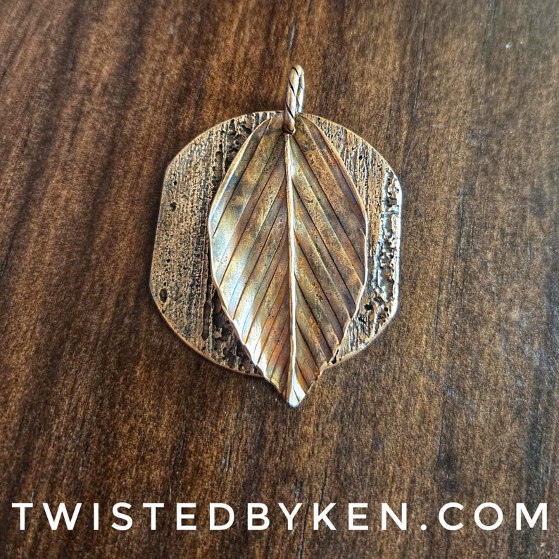 May include: A bronze-colored pendant with a leaf design. The pendant features a textured, rectangular base with a circular top, and a detailed leaf overlay. The text "TWISTEDBYKEN.COM" is at the bottom.