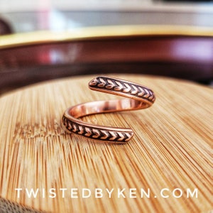 May include: A copper ring with a braided design. The ring is open and adjustable.