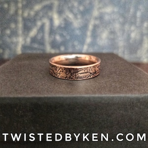 May include: A copper-colored ring with a textured band. The ring is set against a dark background. The text "TWISTEDBYKEN.COM" is at the bottom of the image.