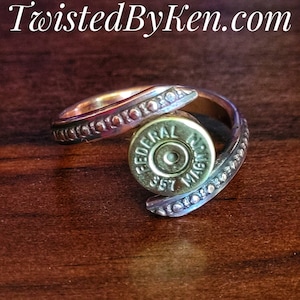 May include: A gold ring with a twisted band and a bullet casing set into the band. The bullet casing is marked "Federal" and "Magnum".