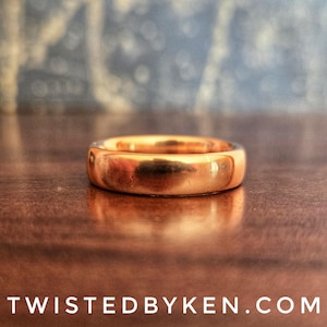 May include: A simple, polished copper band ring. The ring is smooth and has a warm, metallic sheen.