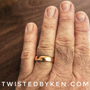 May include: A gold wedding band on a person's finger.