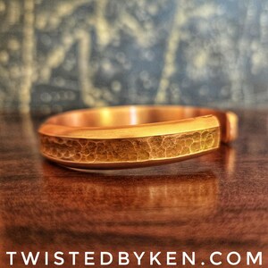 Puede incluir: Un brazalete de cobre martillado con un acabado liso y pulido. El brazalete es un dise&ntilde;o simple y elegante.