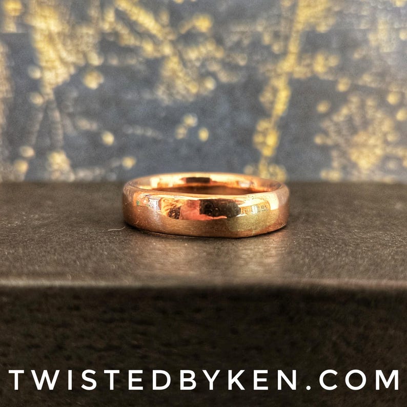 May include: A simple, polished, copper band ring. The ring is smooth and has a warm, metallic sheen.