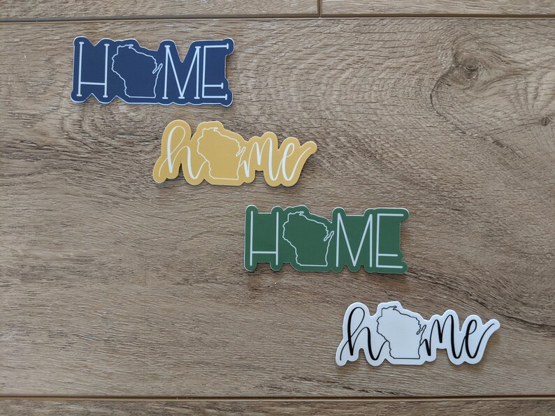 May include: Four different stickers with the word "home" and an outline of the state of Wisconsin. The stickers are in blue, yellow, green, and white.