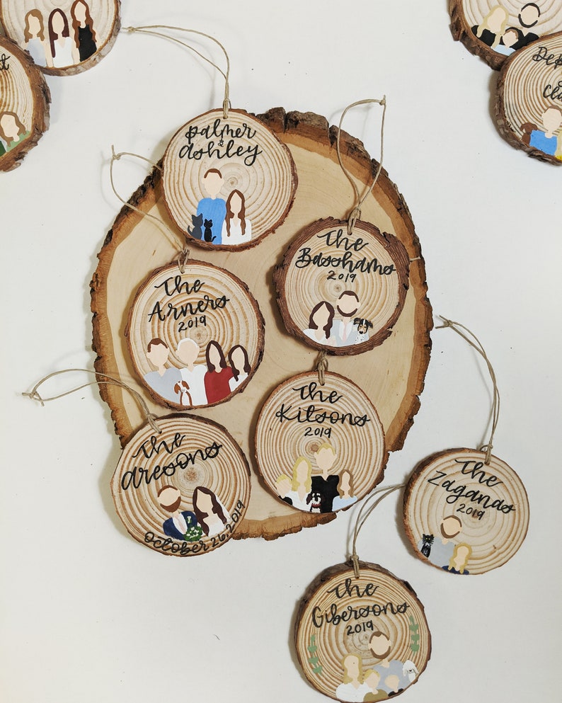 May include: A set of ten personalized wood ornaments with painted portraits and names. The ornaments are decorated with the year 2019 and some include additional text like "The Arneros" and "October 26, 2019".