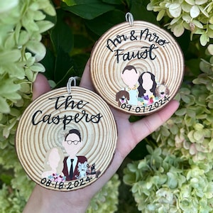 May include: Two round wooden ornaments with painted portraits of couples and their dogs. The top ornament says "Mr. & Mrs. Faust 09.07.2024". The bottom ornament says "The Caspers 08.18.2024".