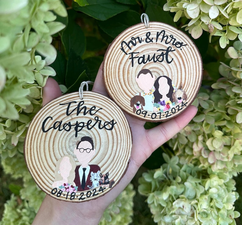 May include: Two round wooden ornaments with painted portraits of couples and their dogs. The top ornament says "Mr. & Mrs. Faust 09.07.2024". The bottom ornament says "The Caspers 08.18.2024".