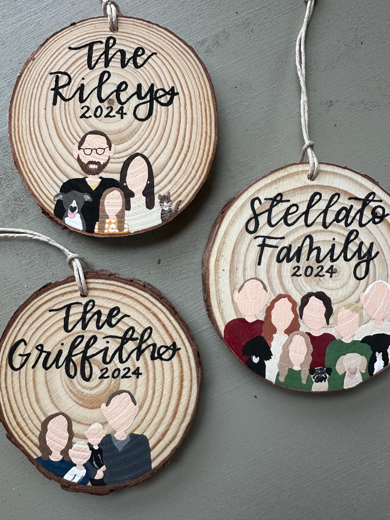 May include: Three personalized wood slice ornaments with painted family portraits and the text "The Rileys 2024", "The Griffiths 2024", and "Stellato Family 2024".